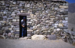 Tourist steeping out of a reconstructed house. sj79_43b027-a-500