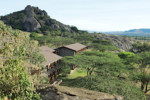 Lobo Lodge surrounded by "umbrella" acacias and enormous rocks. A huge kopje in the background.